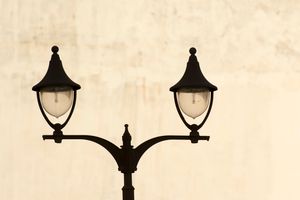 A vintage black dual street lamp stands tall against a neutral cream background, showcasing elegant design.
