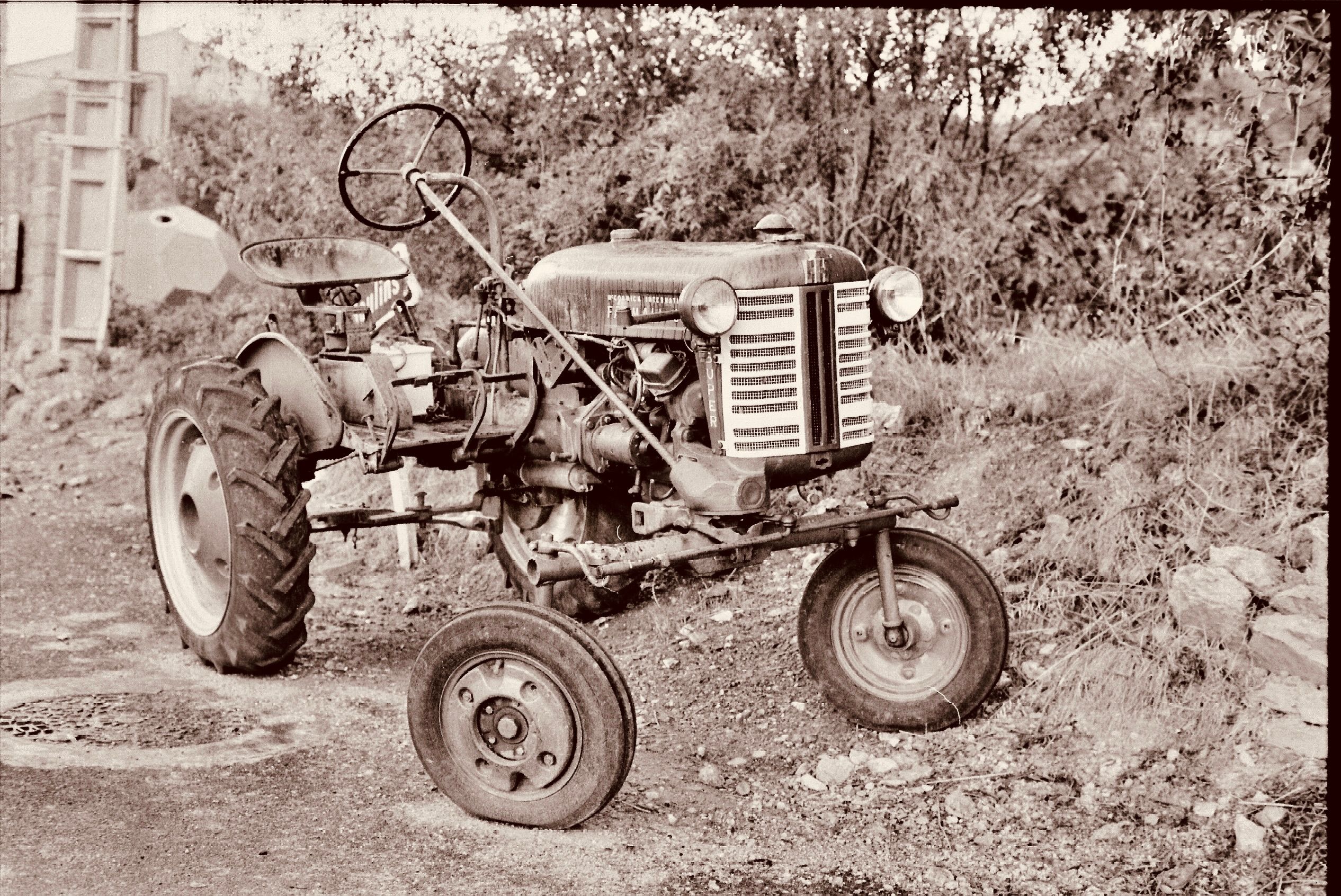 Classic sepia-toned image of an old tractor in a rural landscape.